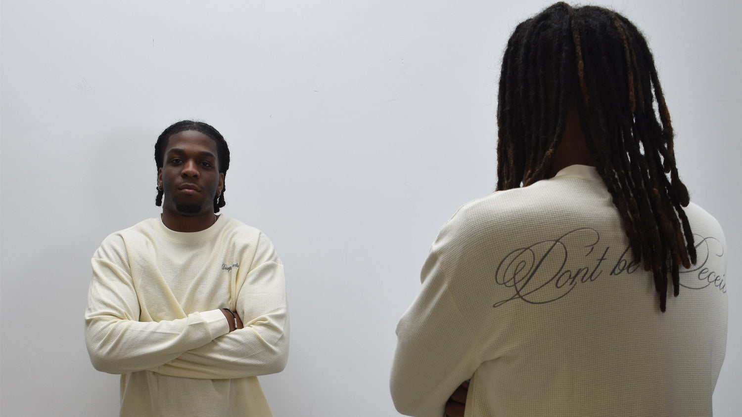 Two people wearing cream-colored shirts with text on a plain background